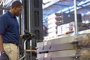 A Ferguson associate in the warehouse uses a product scanner on pallets.
