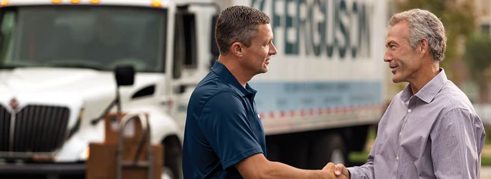 A Ferguson associate shakes hands with a contractor, with a Ferguson truck in the background.