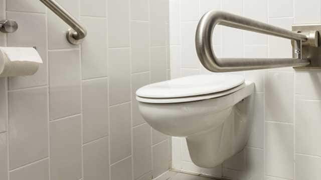 ADA toilet with safety handles in handicap bathroom.