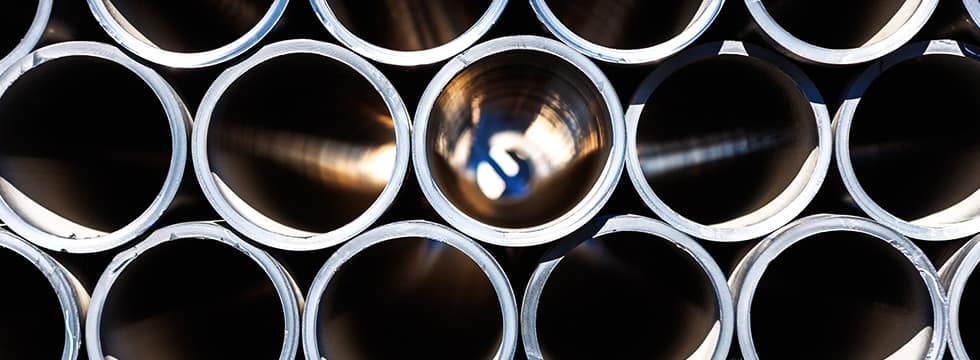 Close view of pipes stacked in the sunshine, with open ends facing viewer.