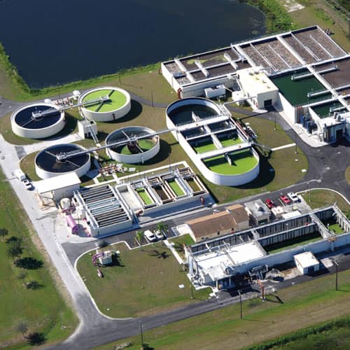 View of a water treatment plant from above, with four reservoirs and a large retention pond.