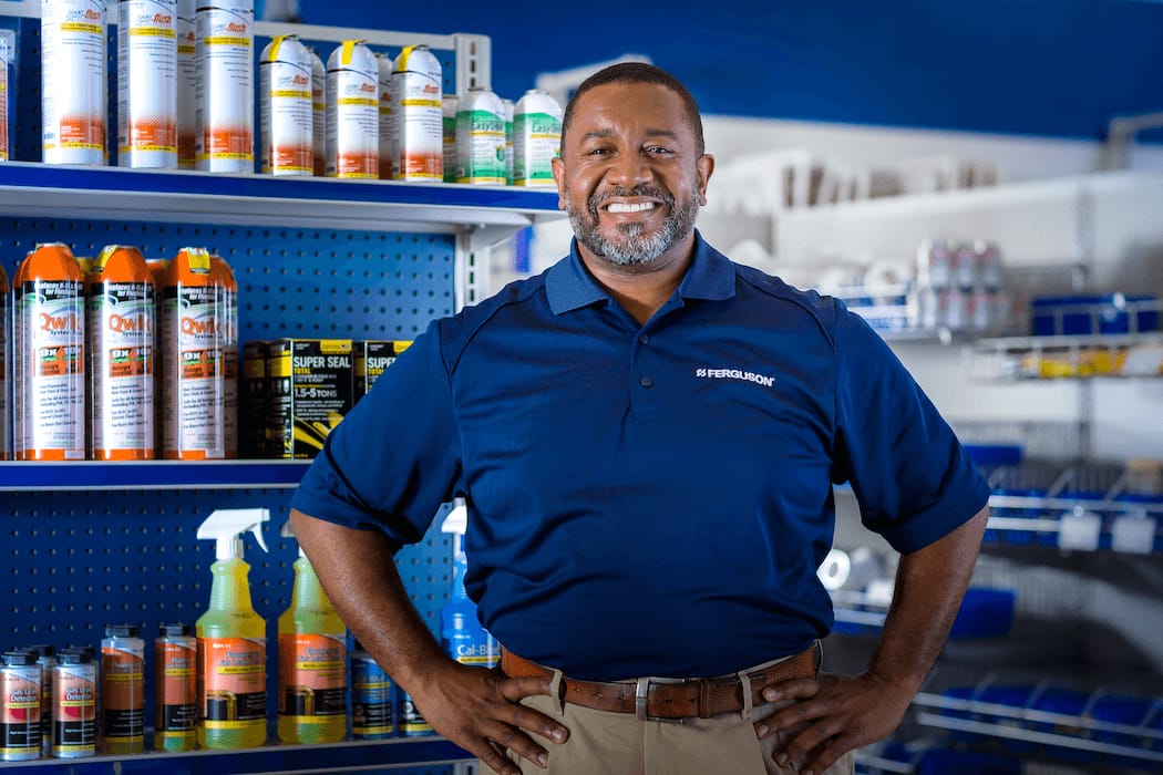 A proud Ferguson associate in an HVAC counter location stands smiling with his hands on his hips.