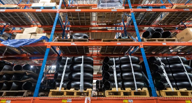 Pipe sections stacked and tied on pallets in a warehouse.