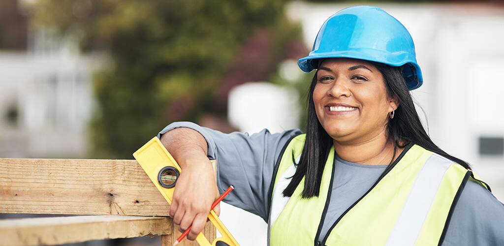 woman contractor wearing safety vest holding a level on a jobsite