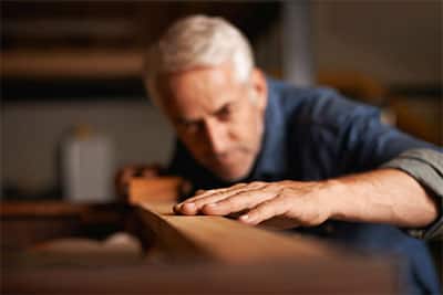 A tradesman checks a plank of wood on the job.